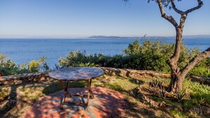 Un patio con una mesa redonda y vista al mar.