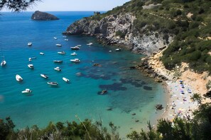 Zona costera con barcos, una playa y terreno rocoso.