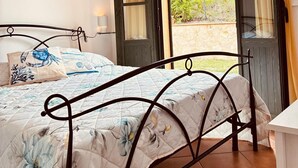 Une chambre à coucher avec un lit, une table de chevet, une fenêtre avec des rideaux et un tableau au mur.