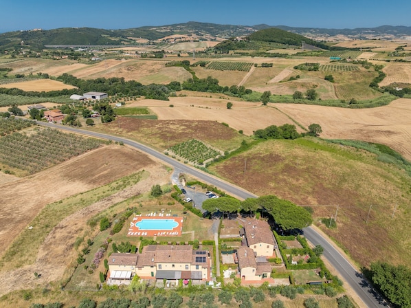 An aerial view of a residential area with a swimming pool, houses, and surrounding fields. - Tuscany Retreat with Pool, Garden & BBQ near the Sea (Castellina Marittima)