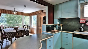 Una cocina con armarios color turquesa, un lavavajillas Bosch y una zona de comedor con una mesa y sillas.