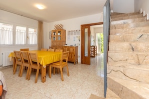 A dining area with a wooden table and chairs, a cabinet, and a staircase.