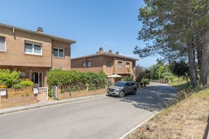 Une rue résidentielle bordée de maisons, avec une voiture garée et un ciel dégagé.