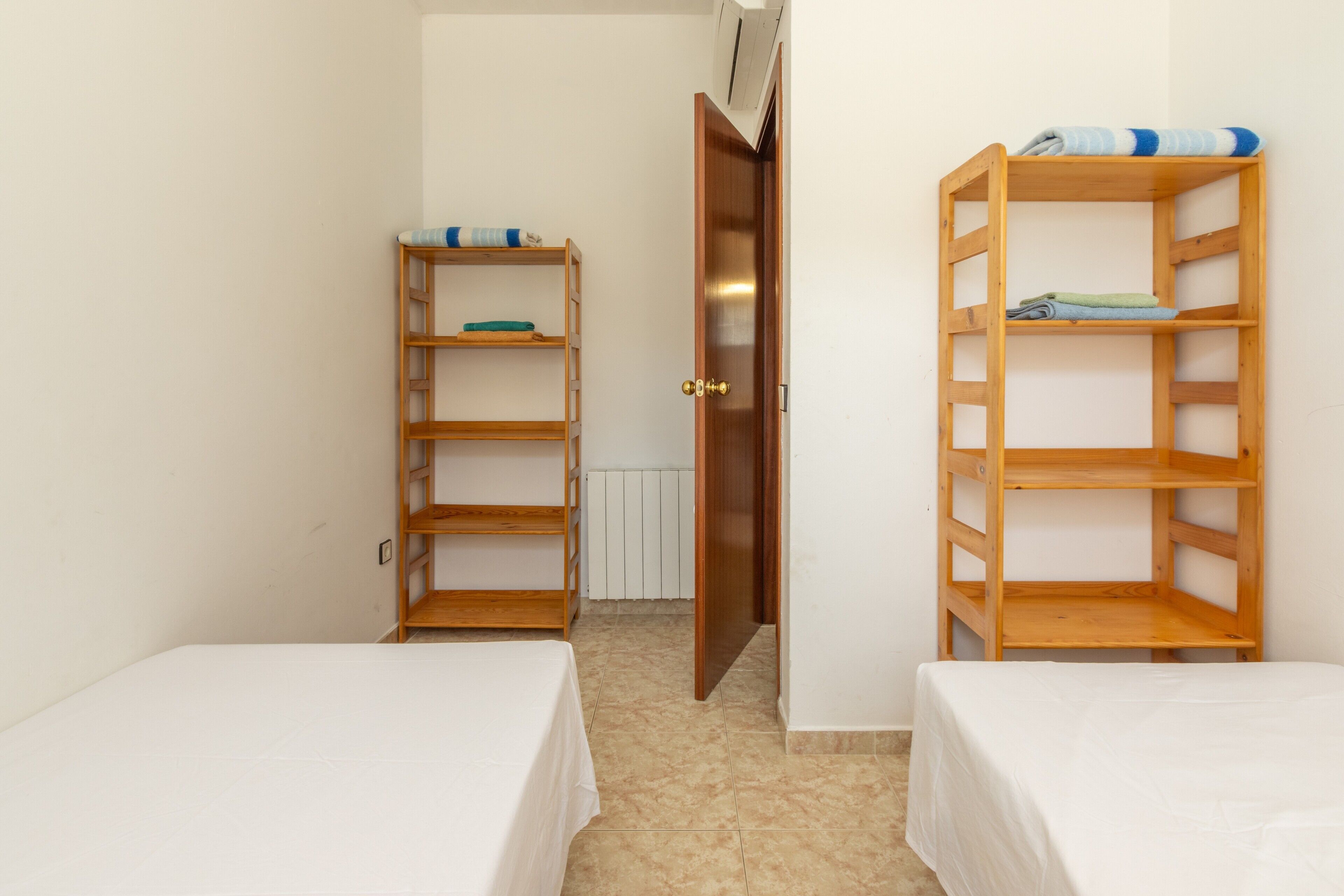 Una stanza con due letti, scaffali in legno, una porta e un termosifone.