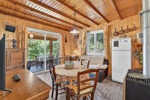 A wooden interior with a dining table, chairs, a refrigerator, and a grill. - Holiday Home 'Petit Chalet' with Mountain View, Private Terrace and Private Garden (Thorame-Basse)