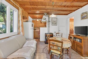 Una sala de estar acogedora con sofá, una mesa de comedor con sillas, televisor y una cocina con armarios de madera y estufa.