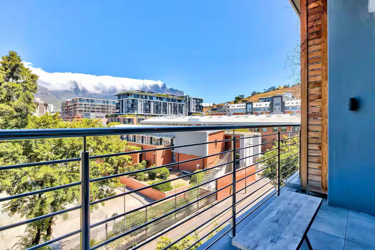 Een balkon met uitzicht op moderne gebouwen en een berg op de achtergrond.