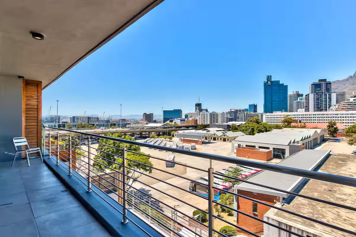 A balcony with a city view, including high-rise buildings and a clear sky.