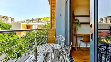 Un balcon avec une balustrade en métal, une table ronde et deux chaises.