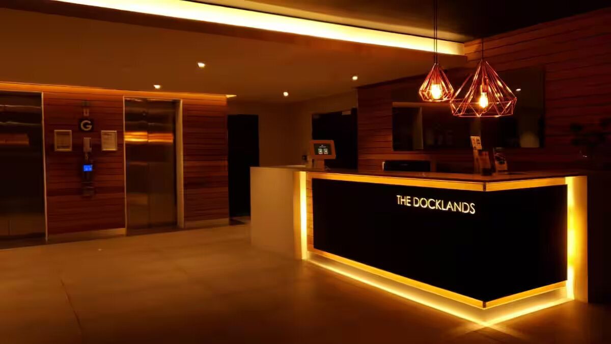 A reception area with a reception desk labeled "THE DOCKLANDS," elevators, and a modern interior design.