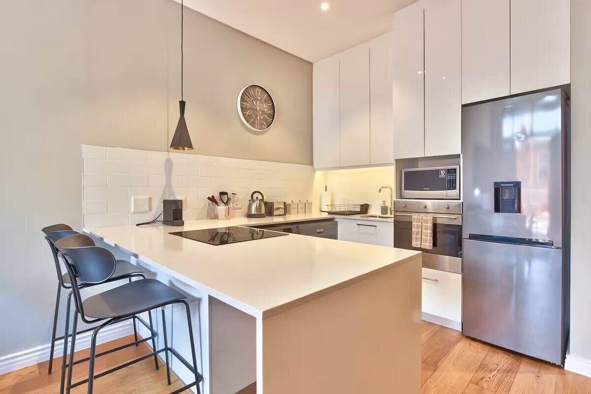A modern kitchen with a large island, stainless steel appliances, and a minimalist design.