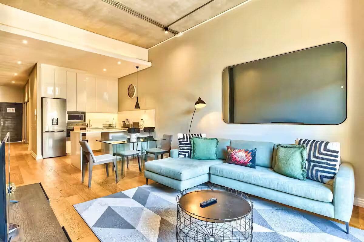A modern living room with a sectional sofa, a coffee table, and a dining area with chairs.