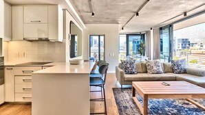 A modern apartment with a kitchen, dining area, and living room with a sofa and coffee table.