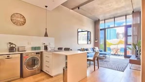 A modern kitchen with a built-in washing machine, a dining area with a view, and a large window.