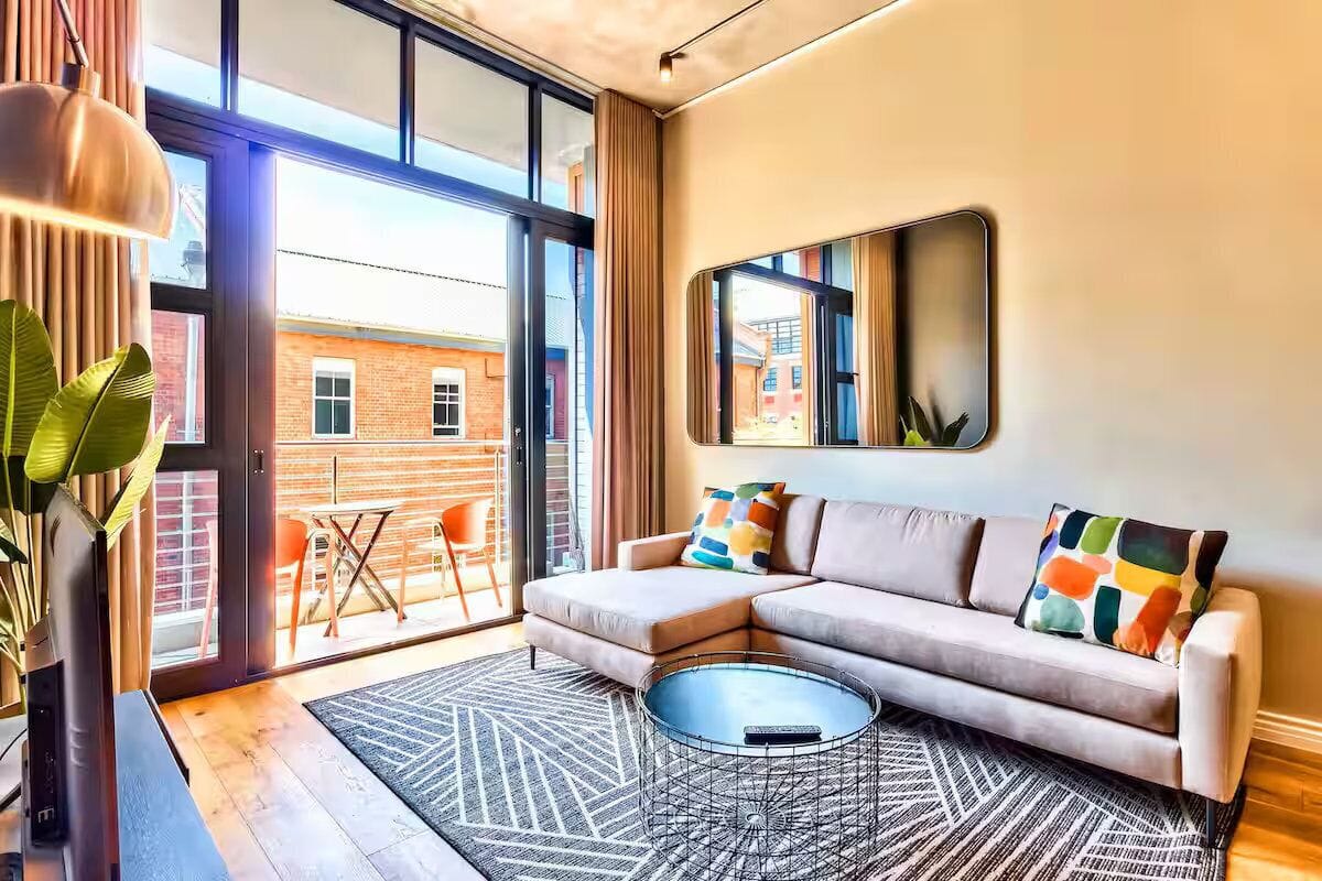 A modern living room with a sectional sofa, a coffee table, and a large window offering a view of the outside.