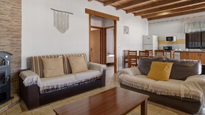 A living room with two sofas, a wooden coffee table, a fireplace, and a kitchen area with a microwave and cabinets. - Holiday Home 'Alpes 2 Solo Familias' with Private Pool, Shared Terrace and Wi-Fi (Conil de la Frontera)