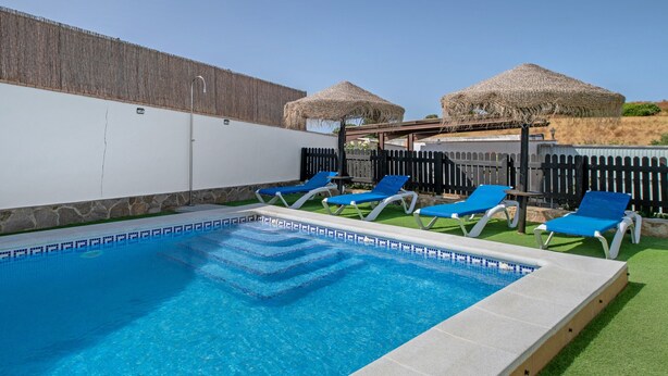 A swimming pool with blue tiles, surrounded by lounge chairs and thatched umbrellas. - Holiday Home 'Alpes 2 Solo Familias' with Private Pool, Shared Terrace and Wi-Fi (Conil de la Frontera)