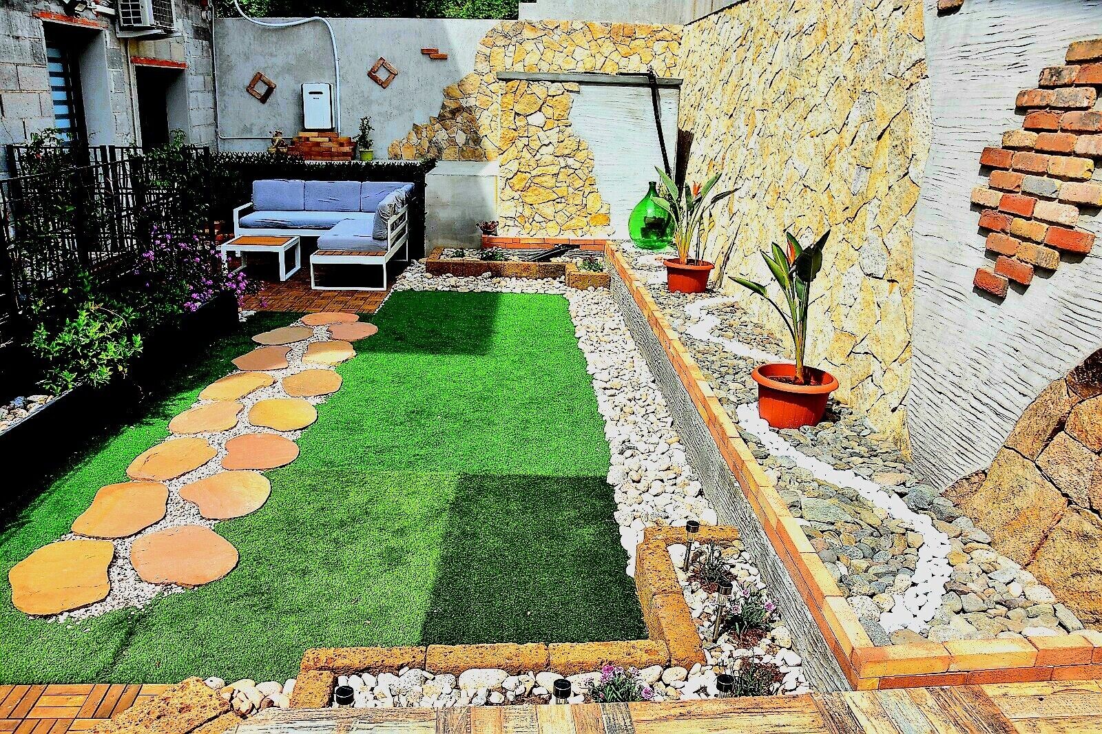 A patio with a stone wall, a small seating area, and a garden with a stone path.