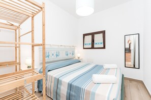 Ein Zimmer mit einem Bett, Holzmöbeln, einem Wandspiegel und einem Fenster mit Vorhängen.