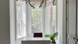 Une pièce avec une table blanche, un lustre et une plante en pot.
