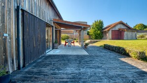 Un edificio de madera con un corredor cubierto que lleva a una mesa y sillas.