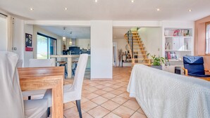 Un amplio salón con una mesa de madera para comer, un sofá y una escalera que conduce a un nivel superior.