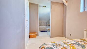 A bedroom with a bed, a door leading to a bathroom, and a small wicker basket.