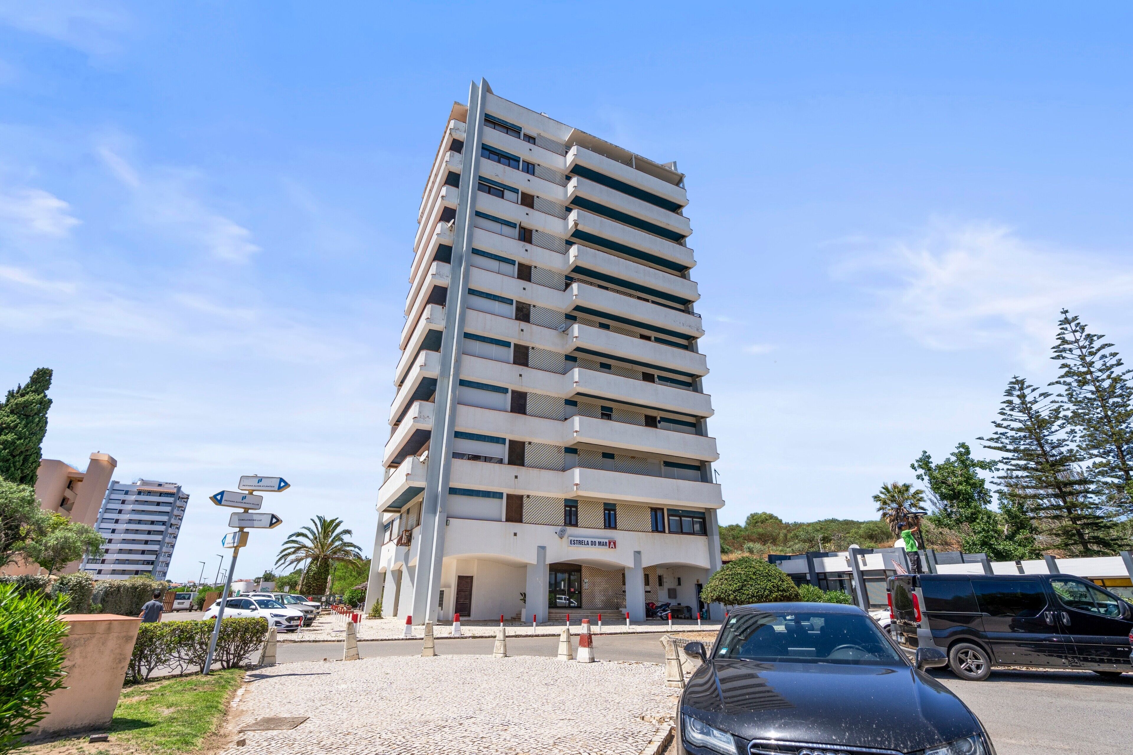 A multi-story building with a modern architectural design, featuring balconies and a ground-level entrance.