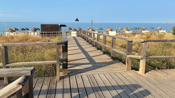 A wooden boardwalk leading to beach umbrellas and a lifeguard tower. - Apartment 'Sunset' with Sea View, Wi-Fi and Air Conditioning (Alvor)