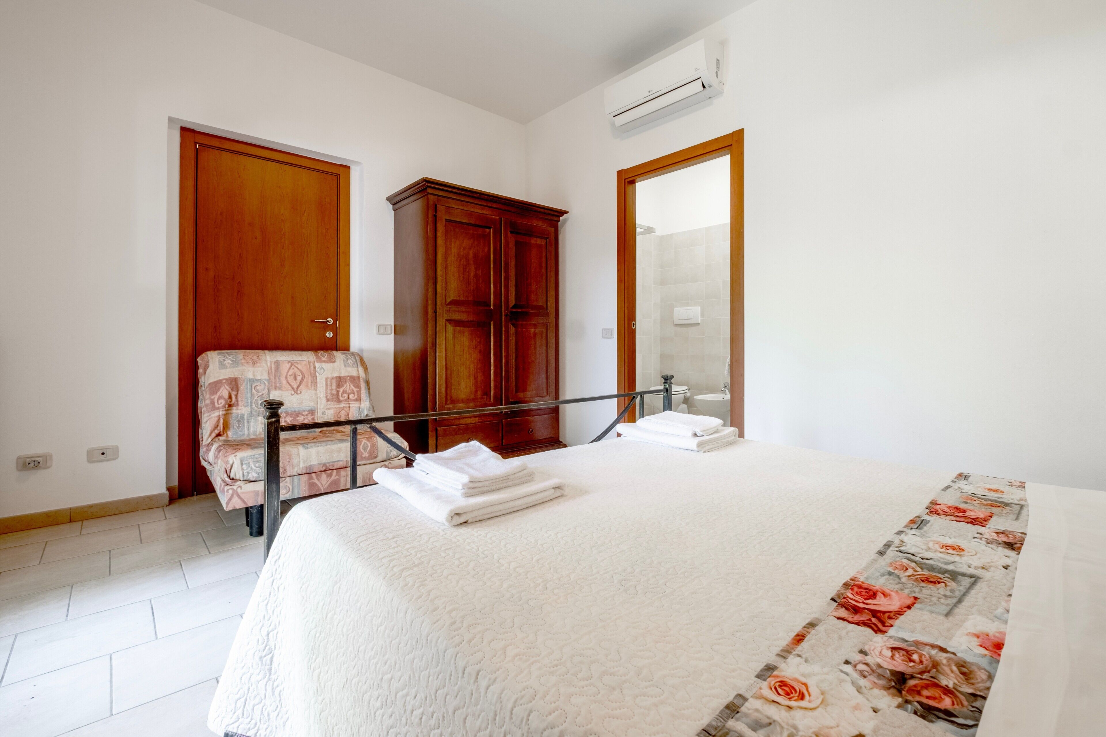 Ein Schlafzimmer mit Bett, Kleiderschrank, Spiegel und Klimaanlage.