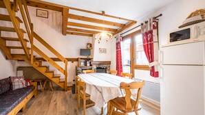 A cozy kitchen with a wooden staircase, a dining table, and a built-in oven.