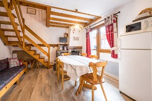 A cozy kitchen with a wooden staircase, a dining table, and a built-in oven.