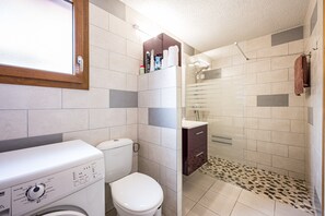 Baño equipado con lavadora, inodoro, ducha y toallero.