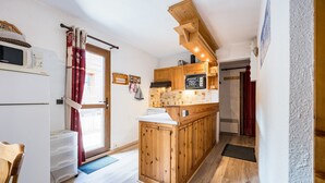 A compact kitchen with wooden cabinets, a built-in microwave, and a small refrigerator.