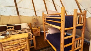 A tent with a bunk bed, a small table, a lamp, and a bear-themed pillow. - This tipi is a 0 bedroom(s), 1 bathrooms, located in O'Brien, OR. (O'Brien)