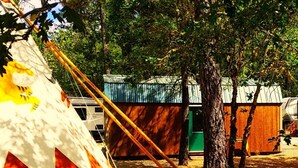 A campsite with a large tent, a small wooden structure, and a tree. - This tipi is a 0 bedroom(s), 1 bathrooms, located in O'Brien, OR. (O'Brien)