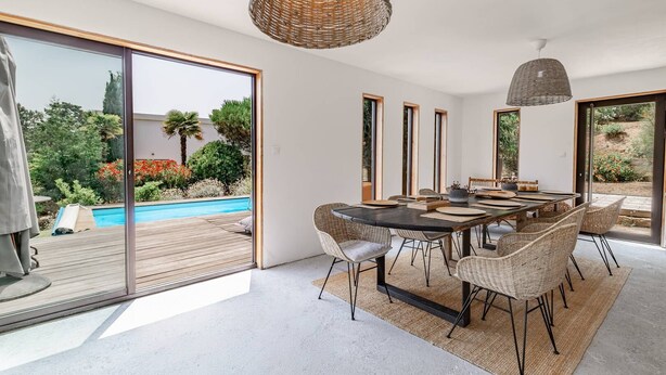 A modern dining area with a large table, wicker chairs, and a view of a swimming pool and garden. - Villa Punta – 2/3 Bedrooms, Pool, Domaine de la Pointe (Grosseto-Prugna)