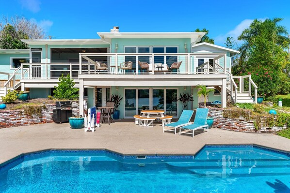 A two-story house with a swimming pool, outdoor furniture, and a barbecue area. - Mango Shores: Trendy Riverfront House w/Game Room, Speakeasy & Pool! (Melbourne)