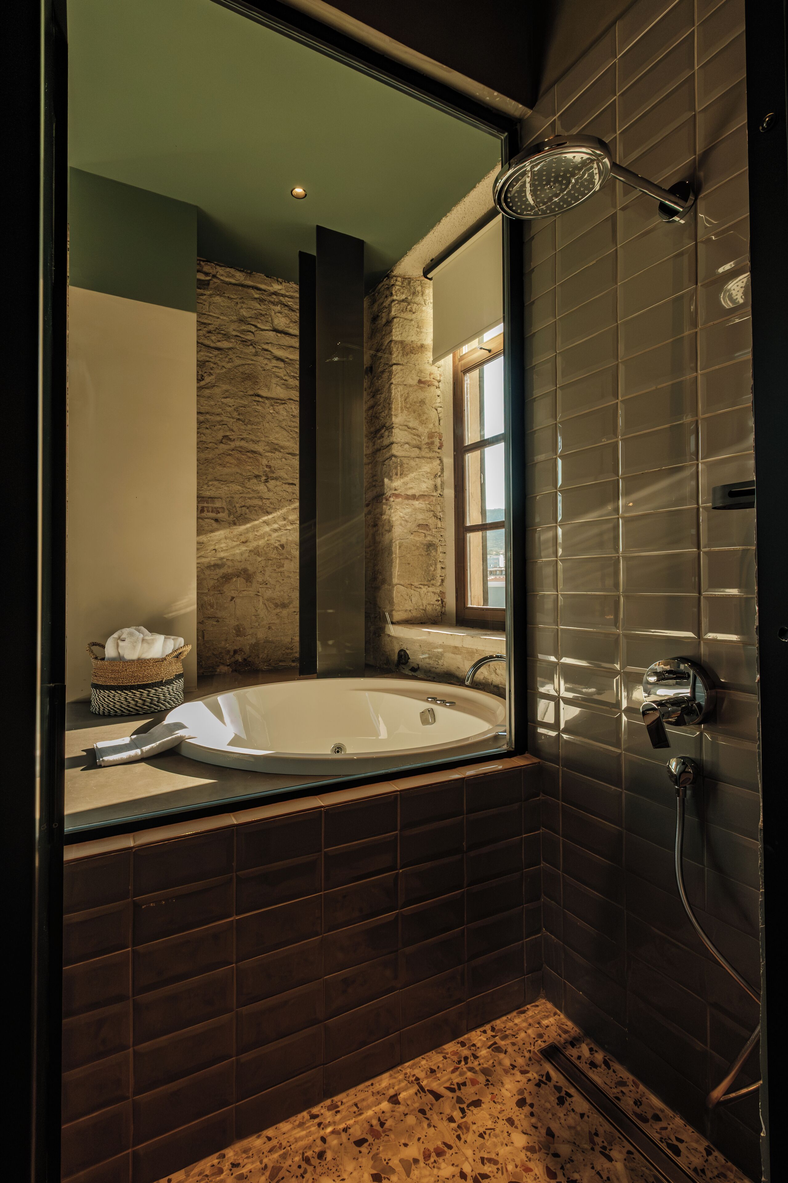 A modern bathroom with a large bathtub, a shower, and a window providing natural light.