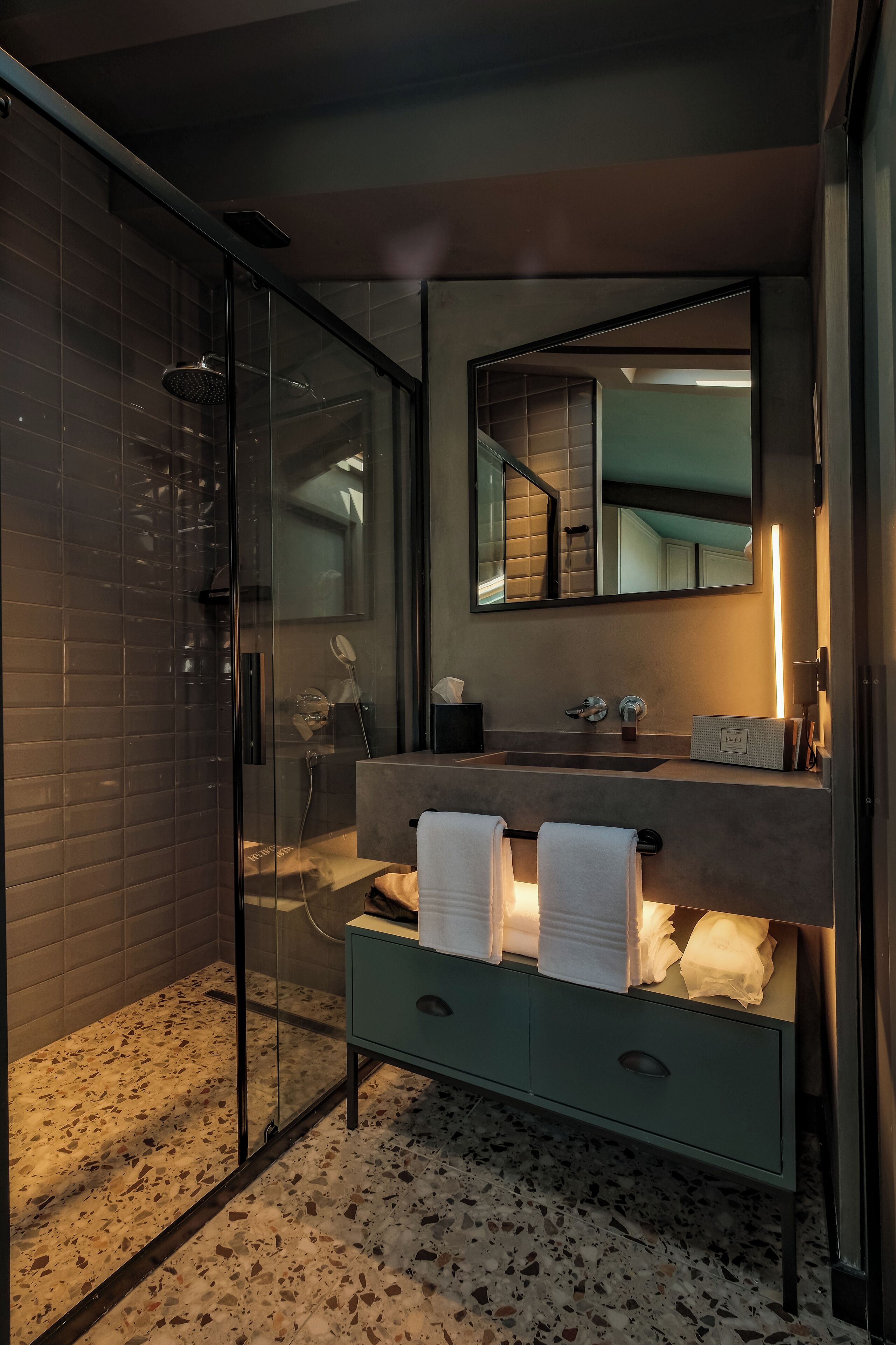 Ein modernes Badezimmer mit einer Glasduschkabine, einem Waschtisch inklusive Spiegel und Waschbecken.