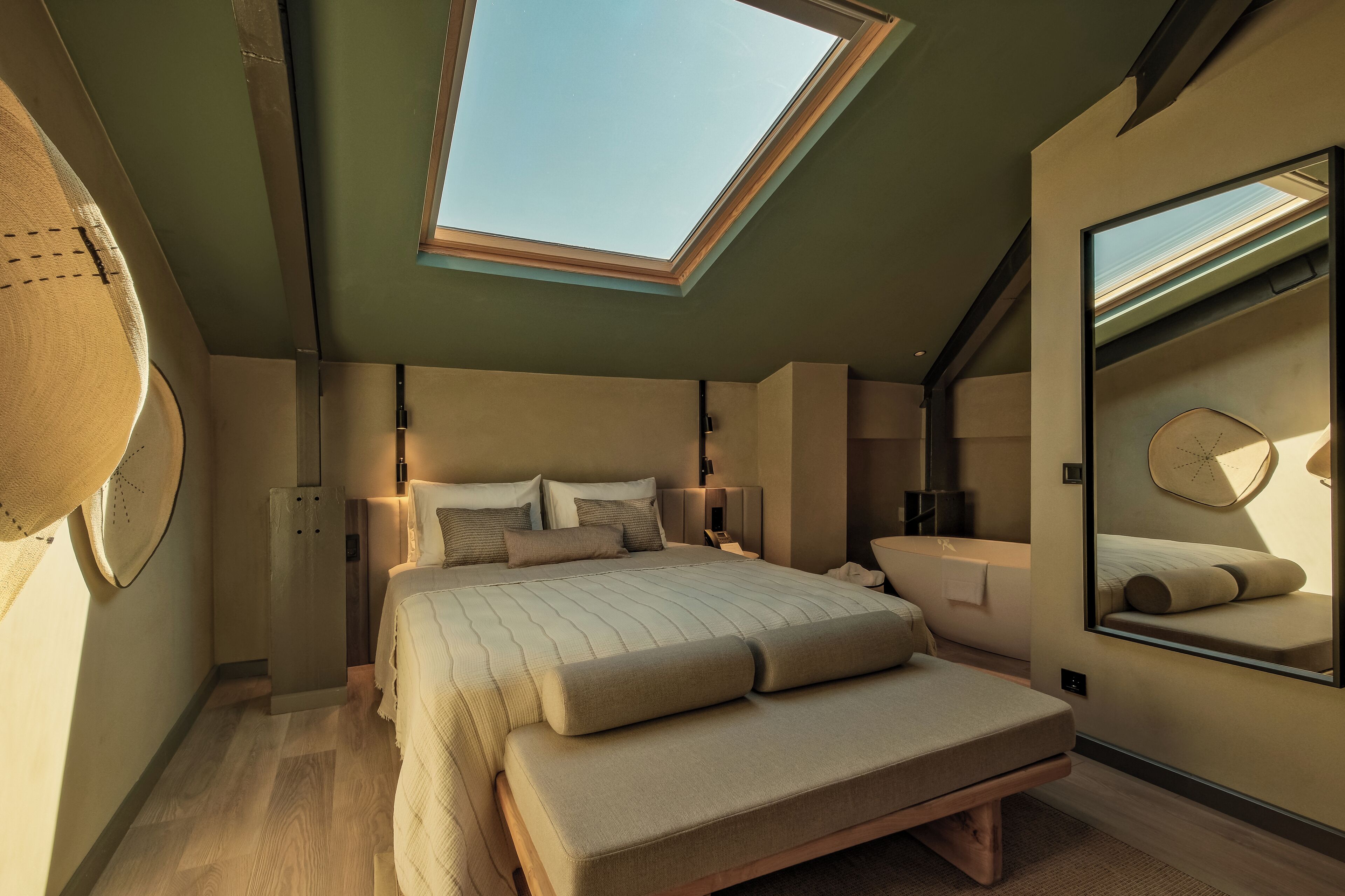 A modern bedroom with a skylight, a large bed, bedside tables, and a mirror.