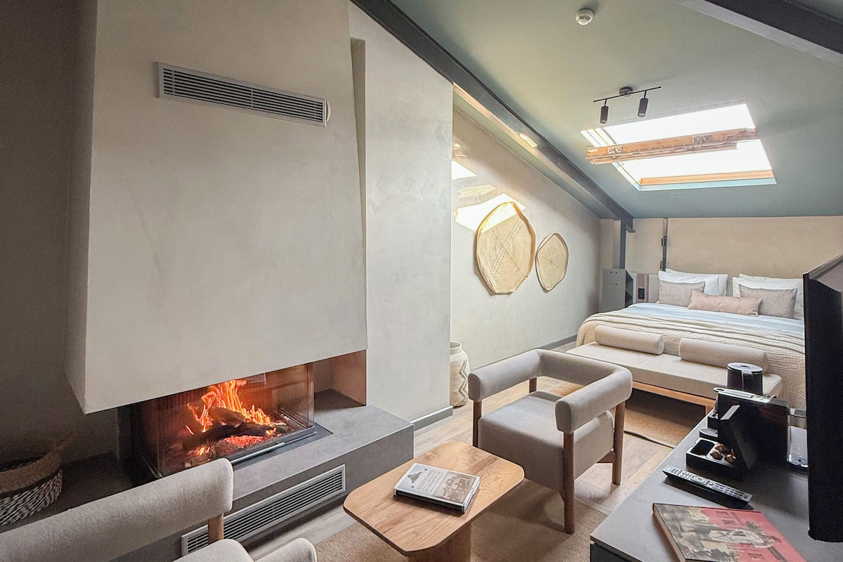 Un dormitorio tipo loft moderno con chimenea, una cama, un sofá y una mesa de centro.