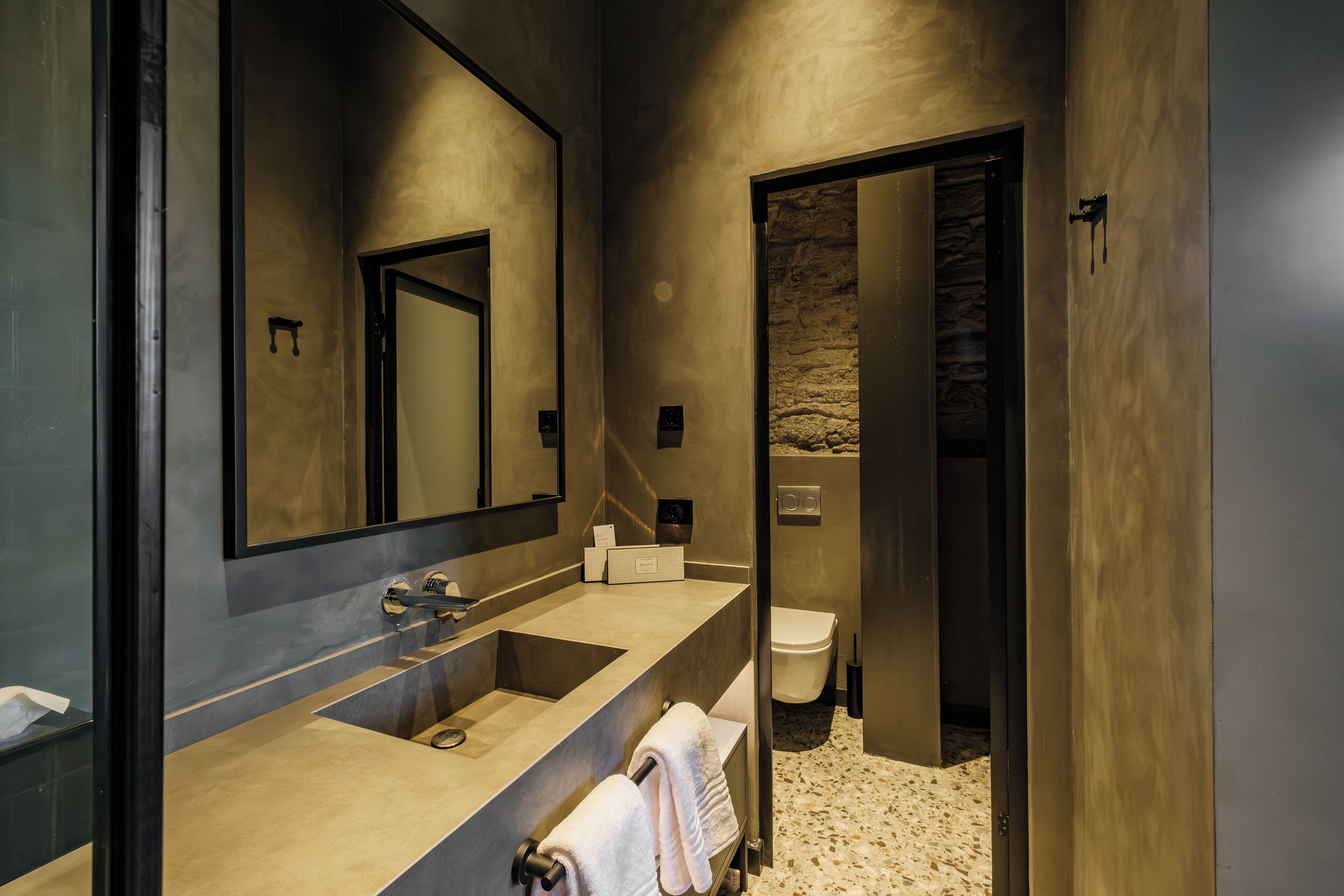 Un baño moderno con un espejo grande, lavamanos dobles y un inodoro.