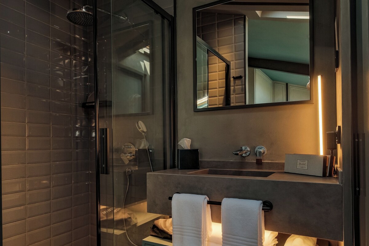 A modern bathroom with a glass-enclosed shower, a vanity with a mirror, and a sink.