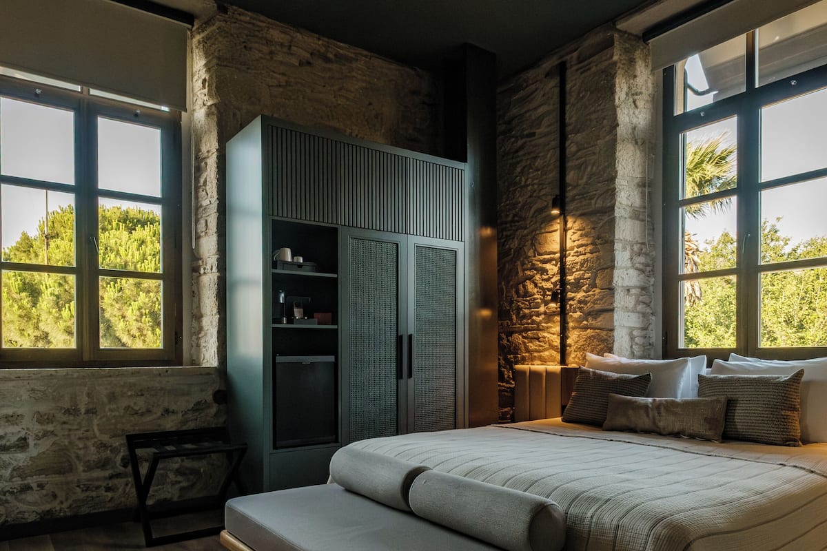 Un dormitorio con cama, banco, armario y ventilador de techo.