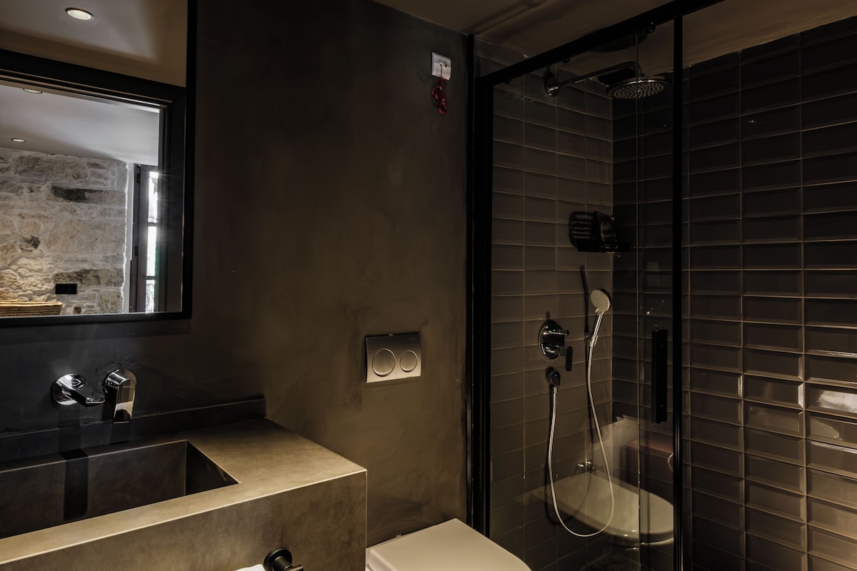 Une salle de bain moderne avec une douche à parois de verre, un lavabo avec un miroir et des toilettes.