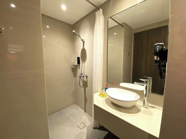 A modern bathroom with a large mirror, a sink, and a shower.