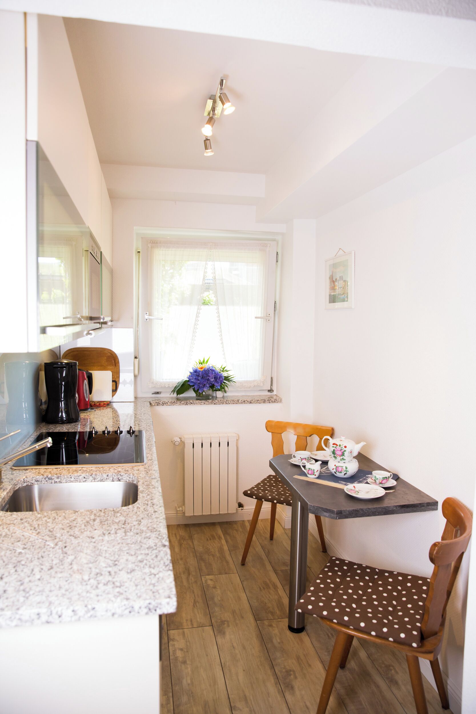 A compact kitchen with a sink, countertop, and a dining area with a table and chairs.