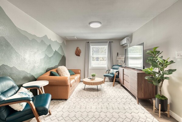 Un salon moderne avec un canapé, des fauteuils, une table basse et une plante en pot.