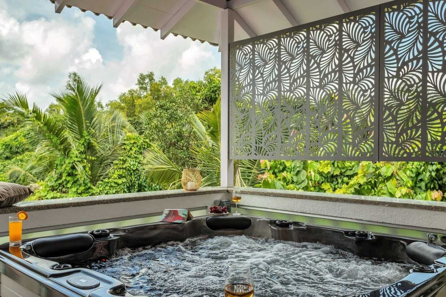A hot tub with a view of lush greenery and a decorative screen.